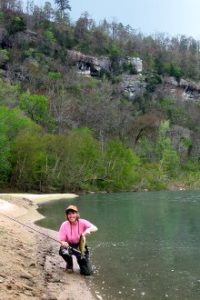 Angler with Smallmouth Bass along limestone bluffs in Arkansas