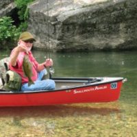 Angler in canoe with a nice limestone stream smallmouth bass