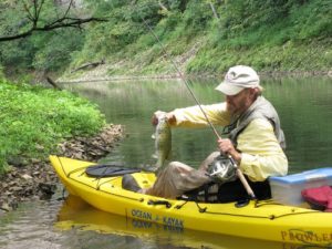 Tim in his kayak landing a limestone smallmouth bass