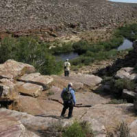 Two anglers hiking ino a river canyon in South Africa