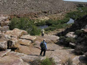 Two anglers hiking ino a river canyon in South Africa